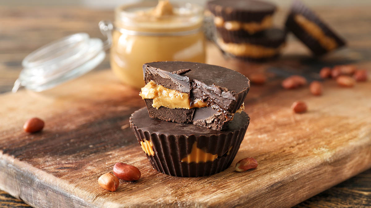 Tasty chocolate peanut butter cups on wooden board