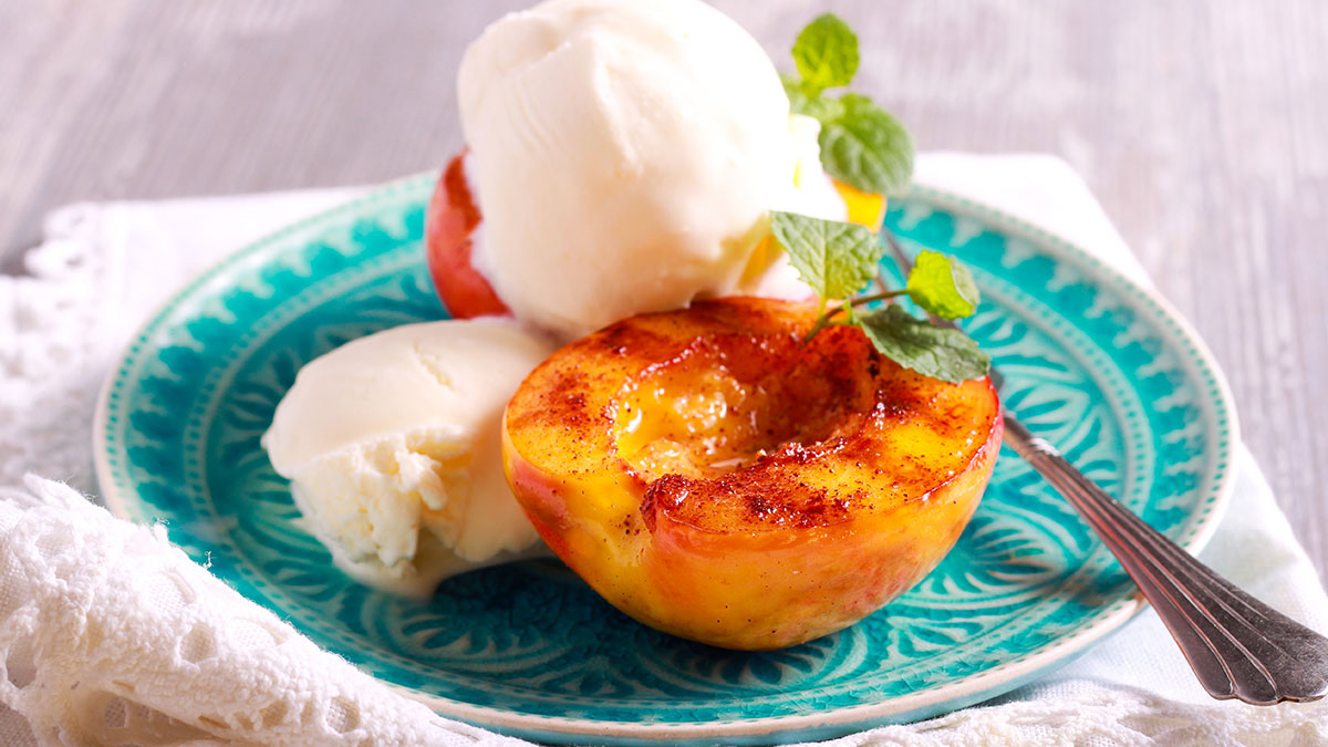 Grilled peaches and ice cream dessert over blue plate