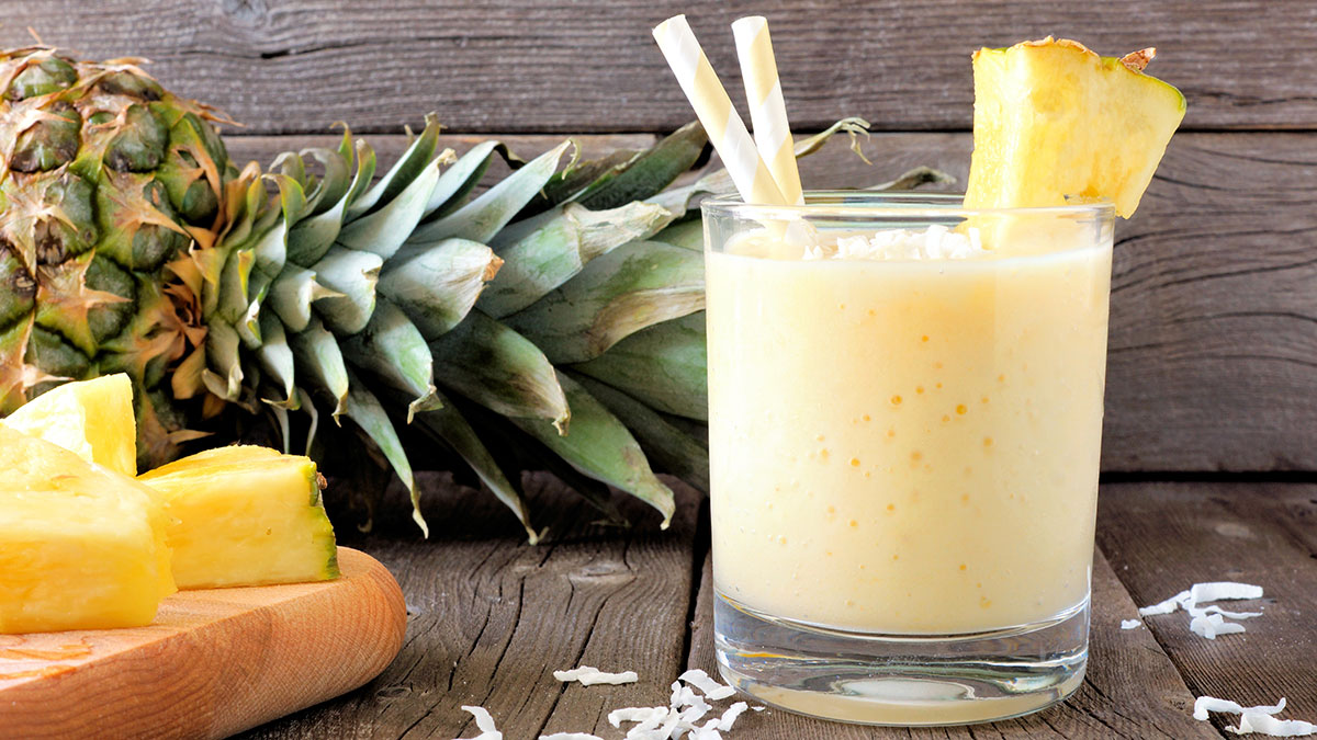 Healthy pineapple smoothie in glass, scene against an old wood background