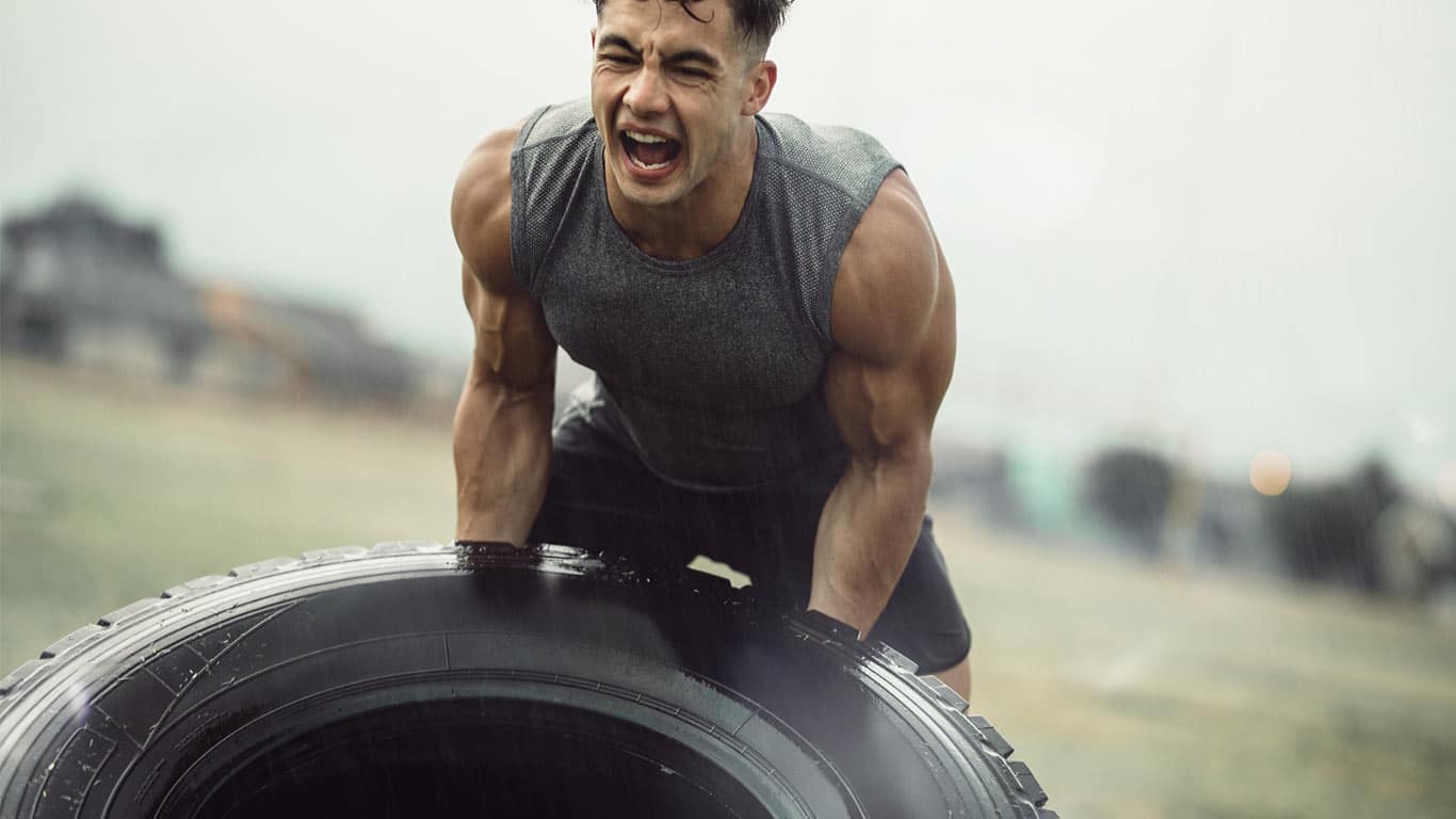Strong athlete doing a tire flip exercise