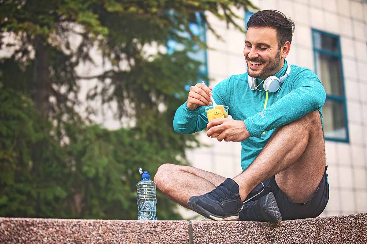 Young athlete man eating fruit post-exercise.