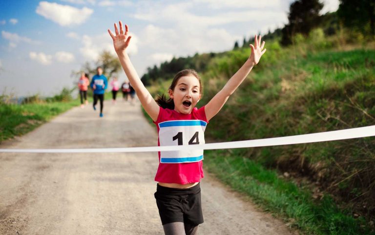 young female athlete running through finish line