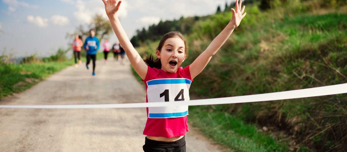 young female athlete running through finish line