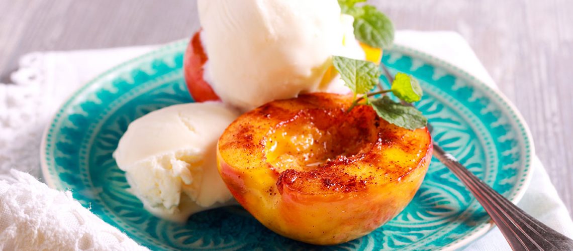 Grilled peaches and ice cream dessert over blue plate